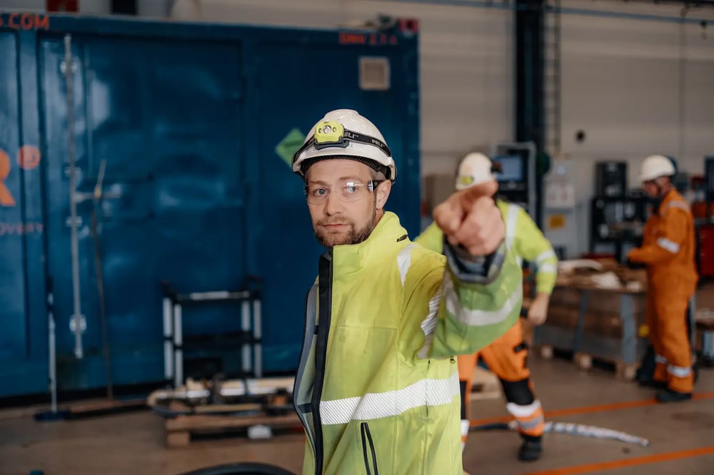 Engineer in safety gear pointing direction inside Enhanced Drilling workshop. Engineer in safety gear pointing direction inside Enhanced Drilling workshop.