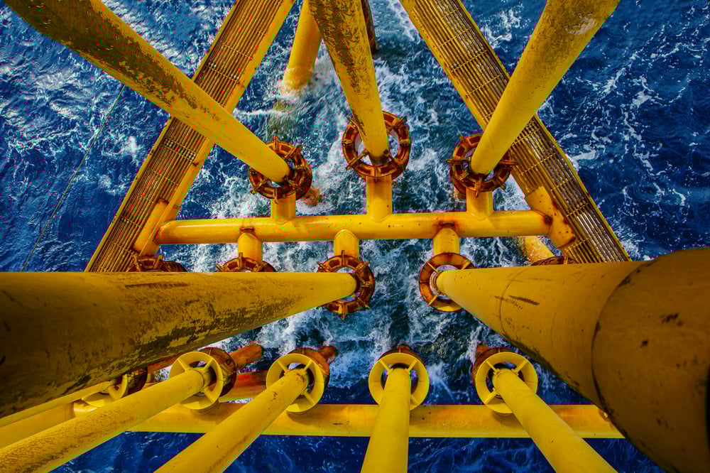 View from above of offshore platform support legs extending into the ocean. View from above of offshore platform support legs extending into the ocean.